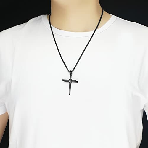 Person wearing a black cross necklace on a white shirt