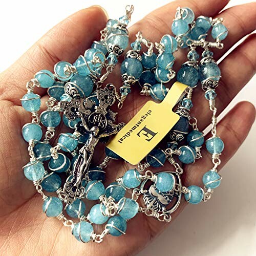 Hand holding blue rosary beads with a crucifix.