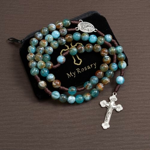 Blue rosary beads with a silver crucifix on a black pouch.