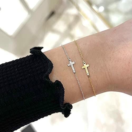 Two cross bracelets, one silver and one gold, on a wrist.