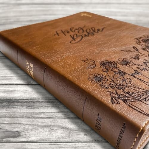 Brown leather Bible with floral design on a wooden surface.