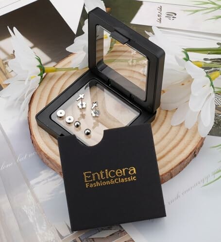 Set of small stud earrings in a black box on a wooden disc with flowers.