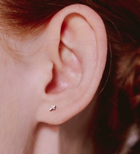 Close-up of an ear with a cross-shaped earring