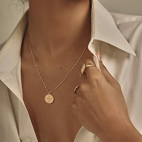 Woman wearing a gold pendant necklace and rings