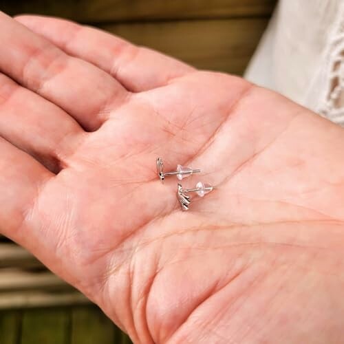 Hand holding small silver earrings