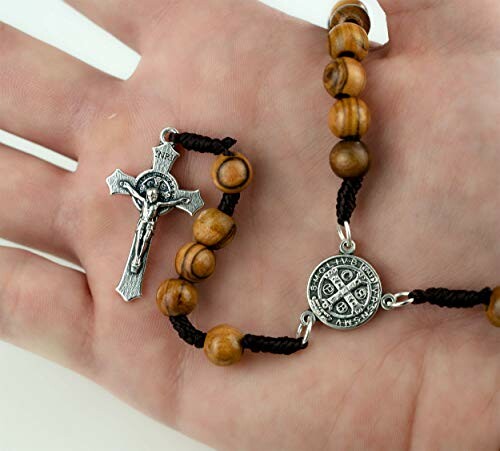 Hand holding wooden rosary beads with a crucifix.