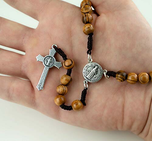 Hand holding a wooden rosary with a metal crucifix.
