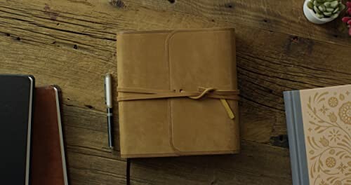 Leather journal with a pen on a wooden table.