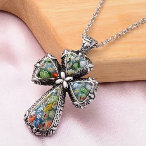 Silver cross pendant with millefiori glass details on a chain.