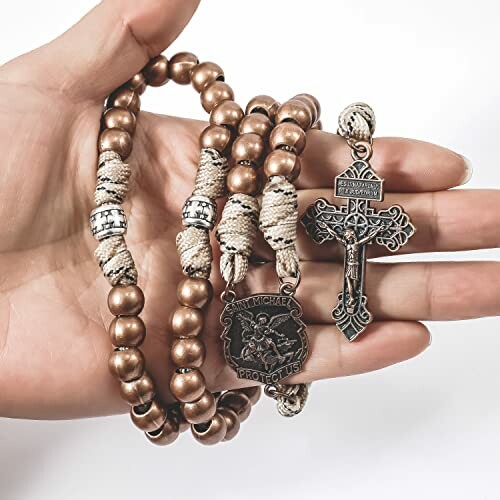 Hand holding rosary beads with crucifix and medallion.