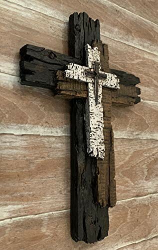 Rustic wooden cross with layered design on a wooden background.