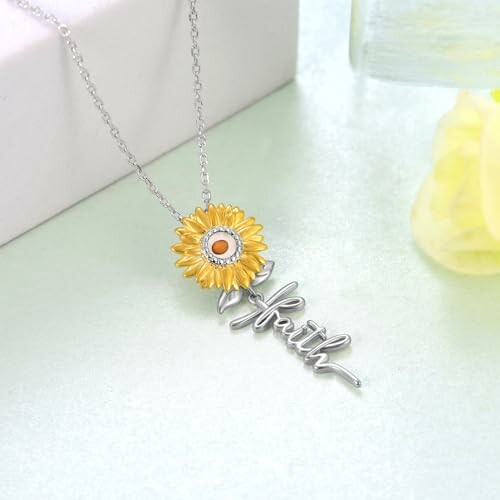 Sunflower necklace with 'faith' pendant on light background