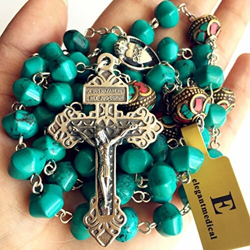 Hand holding turquoise rosary beads with a crucifix.