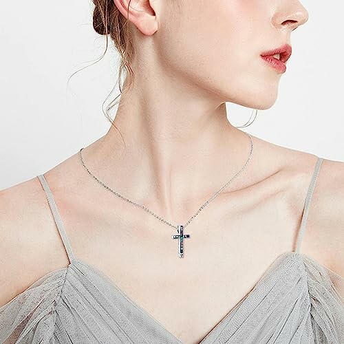 Woman wearing a cross necklace and gray dress.