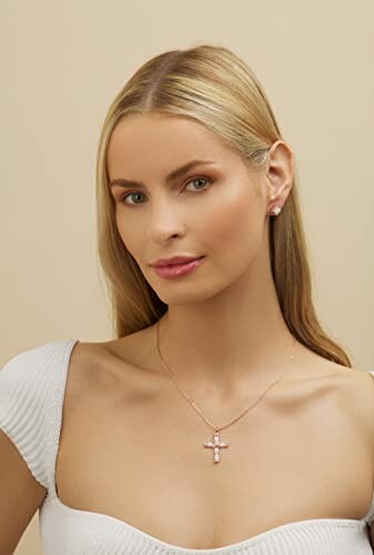 Woman with blonde hair wearing a cross necklace and earrings