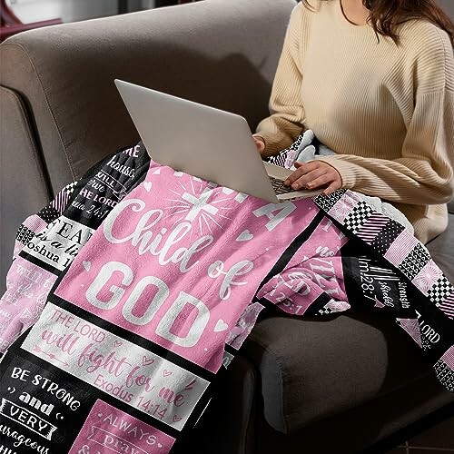 Woman using laptop with inspirational quilt on sofa.