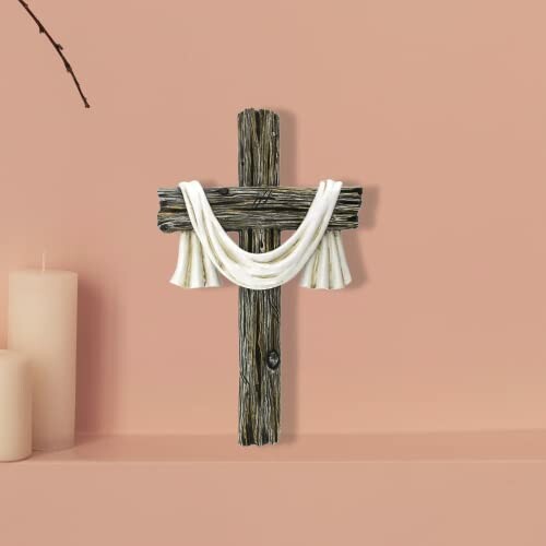 A beautifully crafted wooden cross with draped white cloth on a peach background
