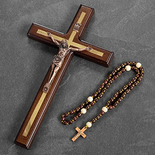 Wooden crucifix with metal figure and rosary on a gray surface.