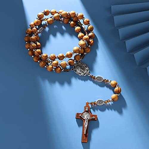 Wooden rosary beads with crucifix on blue background.
